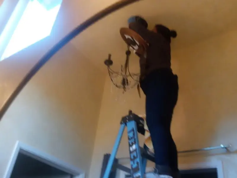 Electrician installing a chandelier in a Wilna residence